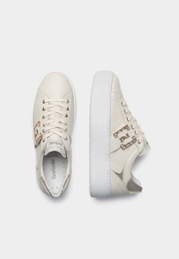 Cremefarvede lædersneakers med en glat struktur, hardware i guldtoner og en tyk hvid gummisål. Snørebånd integreret for en sikker pasform.