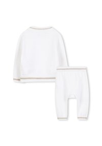 Witte gebreide trui en broek set, met beige bies langs de manchetten en de zoom. Zachte textuur met lange mouwen en een ontwerp van instapbroek.