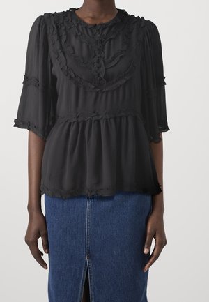 Haut en chiffon noir avec un col et des manches volants, arborant un design à plusieurs niveaux et une texture subtile, associé à une jupe en denim bleu.