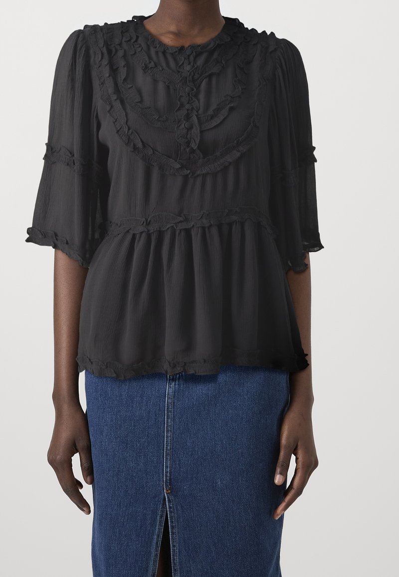 Top in chiffon nero con scollatura e maniche a volant, caratterizzato da un design a più livelli e una texture sottile, abbinato a una gonna in denim blu.
