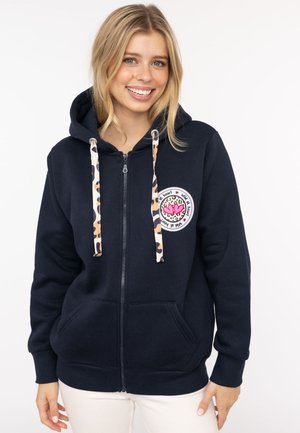 Marineblaue Zip-Hoodie aus Baumwolle mit einer Zugkordel im Leopardenmuster, ausgestattet mit einem runden Aufnäher mit bunten Herzen auf der linken Brust.