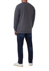Un sweatshirt gris avec un col rond, associé à un jean bleu foncé et des baskets blanches. Le tissu semble doux, avec une texture lisse.
