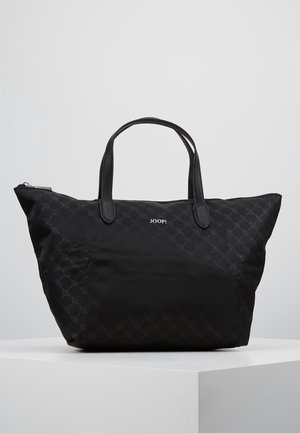 Sac cabas noir avec un motif circulaire subtil, deux poignées et le logo "JOOP!" centré près du haut sur une plateforme blanche.