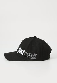 Gorra de béisbol negra hecha de tela, con el texto bordado en blanco "Just Cavalli" en el costado y un ala curva.