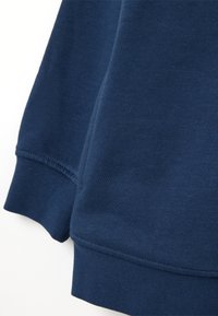 Tessuto di felpa blu navy con polsini e orlo a costine; texture morbida, superficie liscia e dettagli finemente rifiniti sulle cuciture.