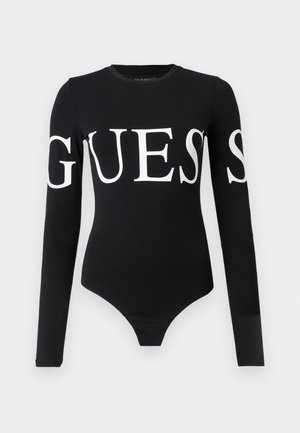 Svart langermet bodysuit med en stor hvit "GUESS" logo over hele fronten. Laget av myk, elastisk stoff med en tettsittende silhuett.