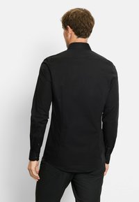 Zwarte langärmelige shirt met een gestructureerde kraag, gladde textuur en knoopmanchetten, met een getailleerde pasvorm en een rugpand ontwerp.