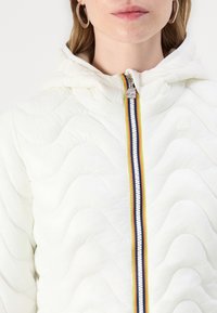 Giacca bianca trapuntata con cappuccio, zip frontale con strisce multicolori e motivo a onde testurizzato.