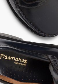 Námořnické kožené boty s kulatou špičkou, viditelným prošíváním a perforovanou stélkou. Vyznačují se zlatým logem "Pisamonas". Texturovaná podrážka pro lepší grip.