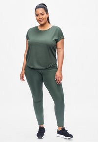 Olive green athletic top and leggings made of smooth, stretchable fabric. Top features a round neck and short sleeves; leggings are form-fitting.