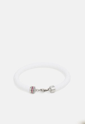 Bracelet tressé blanc avec fermoir en argent et petits anneaux décoratifs, posé à plat sur un fond blanc.
