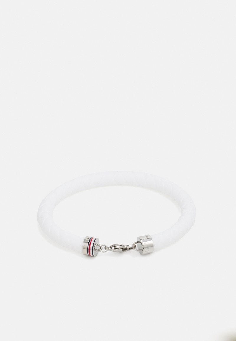 Bracelet tressé blanc avec fermoir en argent et petits anneaux décoratifs, posé à plat sur un fond blanc.