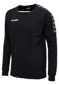 Svart långärmad sweatshirts i mjukt tyg, med rund hals och grå chevrondesign på axlarna. Hummel-logotypen syns på bröstet.