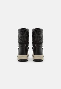 Par de botas de invierno negras con parte superior acolchada, suelas beige y tiradores traseros, vistas desde atrás sobre un fondo blanco.