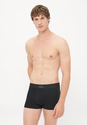 Zwarte boxer shorts met een groen Lacoste-logo op de tailleband. Gemaakt van een gladde stof met een aansluitend ontwerp en zonder zichtbare patronen.