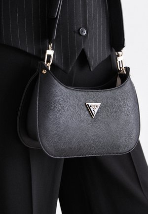 Sac à main en cuir noir avec une finition texturée, une forme arrondie, des ferrures dorées et un logo triangulaire affiché en évidence sur le devant.