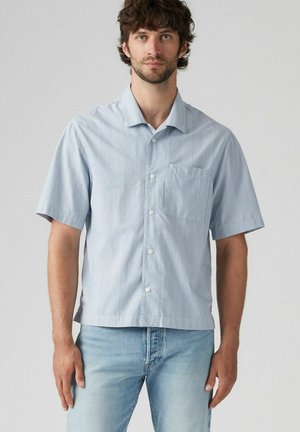 Short-sleeve button-up shirt in light blue with vertical white stripes, a chest pocket, and a relaxed fit. Made from smooth fabric.