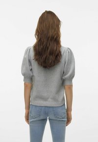 Szary sweter z dzianiny z bufiastymi rękawami, okrągłym dekoltem i ściągaczem na dolnym brzegu, noszony z jasnoniebieskimi dopasowanymi dżinsami. Widok z tyłu pokazuje włosy opadające na plecy.