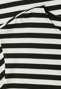 Tissu rayé horizontalement noir et blanc, plié près d'un col cousu, montrant la texture et les détails de la couture.