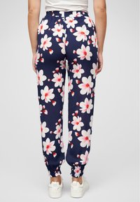 Pantaloni jogger blu navy realizzati in tessuto leggero, con un motivo floreale bianco e rosa, vita elastica e polsini aderenti alle caviglie.