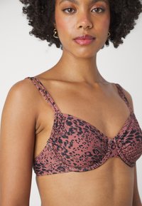 Leopardmønstret bh i dæmpet pink og sort. Har bøjler, justerbare dobbeltremme og sammenkrøllede detaljer ved sømmene.