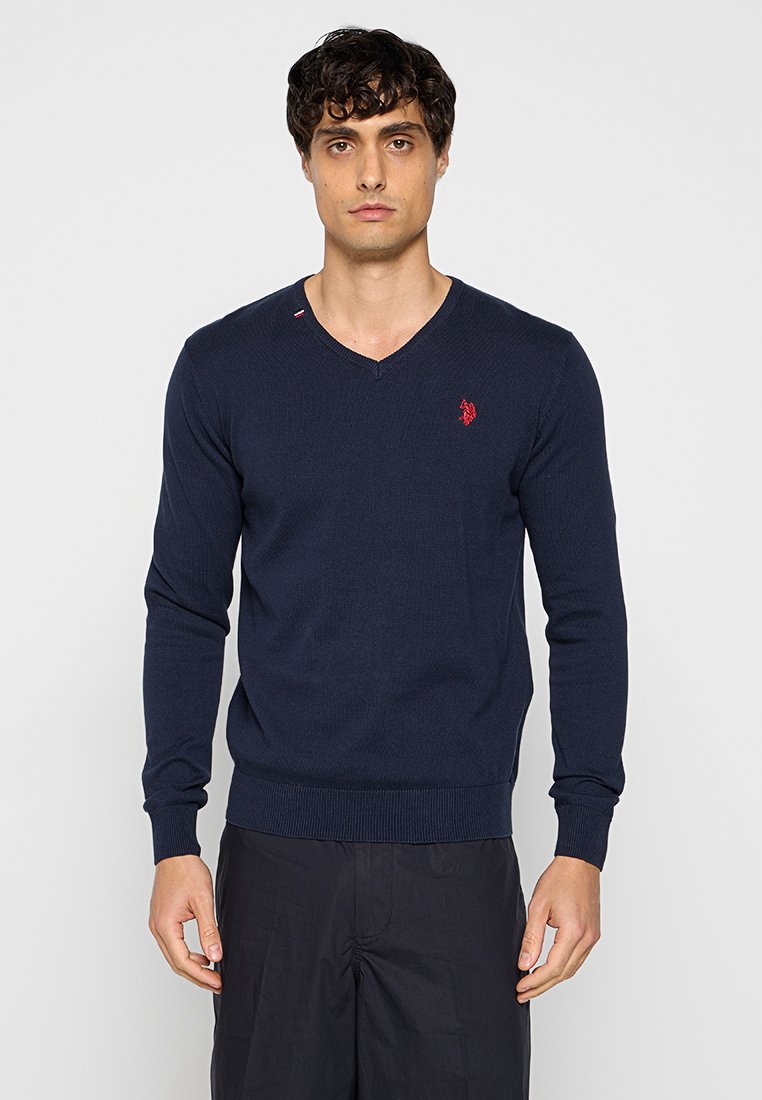 Marineblauer V-Ausschnitt-Pullover aus Rippstrick, mit einem kleinen roten Logo auf der Brust und einem Kontrastnäht-Detail am Kragen.