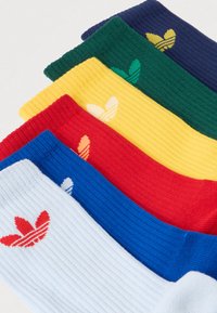 Pet parova rebrastih čarapa u plavoj, crvenoj, žutoj, zelenoj i tamnoplavoj boji, svaka s kontrastnim logom blizu vrha.