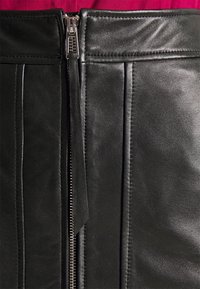 Gonna in pelle nera con zip anteriore a denti metallici, dettagli di cucitura orizzontale e una texture liscia.