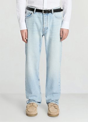 Jean en denim bleu clair à coupe large, doté de poches avant et d'une ceinture en cuir noir. Les chaussures sont des mocassins beiges avec des semelles en caoutchouc.