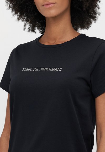 Melnas kokvilnas T-krekls ar īsām piedurknēm, apaļu kaklu un soutenētiem "EMPORIO ARMANI" logotipu uz priekšpuses.