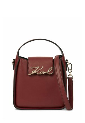 Petit sac à main en cuir bordeaux avec poignée supérieure, bandoulière amovible et détail doré de lettrage "Karl" sur le rabat avant.