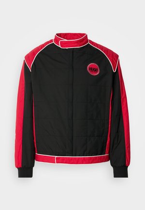 Schwarze gesteppte Jacke mit roten Akzenten und weißen Paspeln. Mit hohem Kragen und rundem Logo auf der Brust. Leichtes Material.