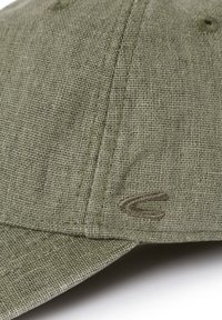 Grønne cap med en tekstureret stof, der har et broderet logo på siden. Designet inkluderer en buet skygge og synlige syninger.