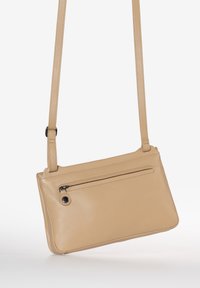 Borsa a tracolla in pelle beige con una lunga striscia. Caratterizzata da una tasca frontale con zip e un design rettangolare liscio. Minimalista con linee pulite.