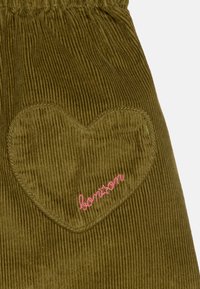 Olivegrønne kordfløjlsbukser har en hjerteformet lap med pink broderi, der står "bonton." Tekstureret stof, elastisk liv. 