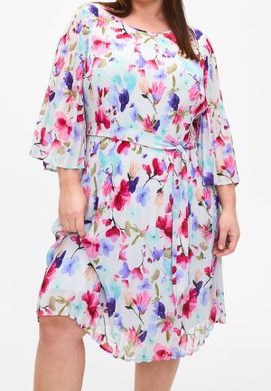 Robe florale en tissu léger ; présente des couleurs pastel avec des motifs roses, bleus et verts. Comprend une taille ceinturée et des manches évasées.