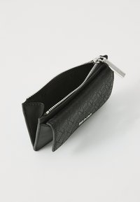 Portafoglio nero con un esterno testurizzato e motivi geometrici, chiusura a zip e hardware argentato. Design compatto realizzato con materiali diversi.