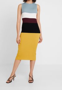 Ribbade stickade klänning med ärmlös design och färgblockerade sektioner i ljusblått, vitt, burgundy, svart och gult. Knälång.