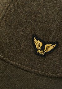Tissu en laine marron avec des coutures brodées présentant un logo ailé noir et jaune avec le texte "PME".