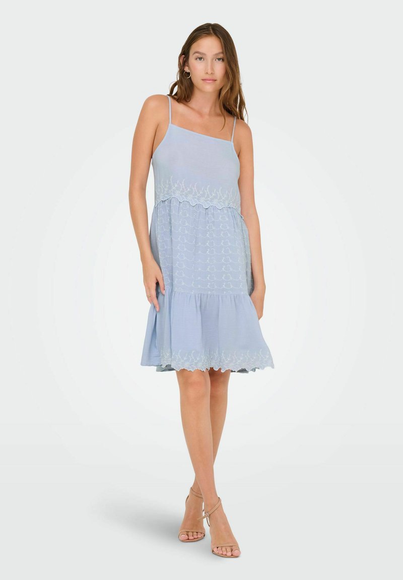 Robe sans manches bleu clair avec des détails brodés à la taille et à l'ourlet, jupe à volants et texture fluide.