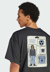 Černé tričko s krátkými rukávy, na zádech s grafickým motivem postavy a různými logy Adidas v modré a bílé barvě.