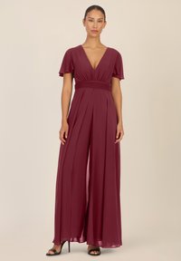 Bordeauxkleurige jumpsuit met V-hals, korte fladdermouwen, geplooid ontwerp, getailleerde taille en brede broekspijpen. Gemaakt van lichte stof.