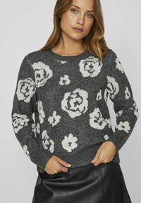 Grauer Strickpullover mit weißen Blumenmustern, Rundhalsausschnitt, langen Ärmeln und gerippten Bündchen und Saum. Weiches Material, lockere Passform.