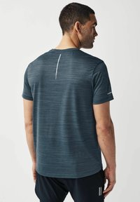 Camiseta atlética de manga corta en azul oscuro con un patrón texturizado, acento reflectante en la parte posterior y un ajuste relajado. Diseño de cuello sin costuras.