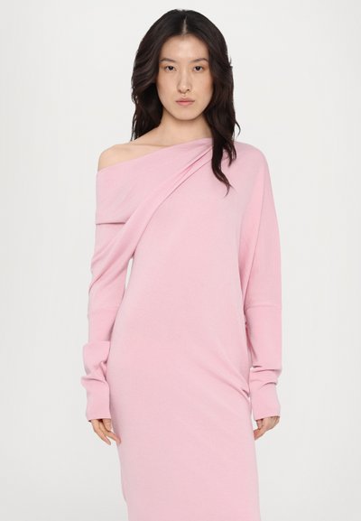 Rochie lungă cu mâneci lungi, de culoare roz deschis, cu un design off-the-shoulder. Țesătura pare ușoară și texturată, având detalii drapate.