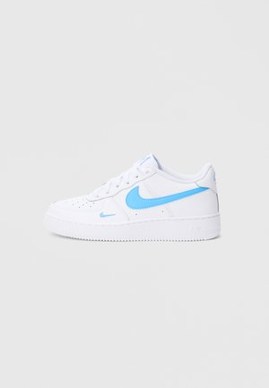 Valged nahast tossud helesiniste detailidega, millel on ümar nina, lamedad paelad ja tekstuuriga kummist tald. Nike logo on hästi nähtav.