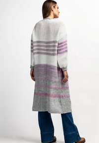 Długi, lekki sweter w kolorze białym, szarym i lawendowym w paski, z luźnym fasonem i teksturowanym materiałem.