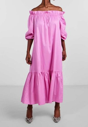 Femme portant une robe midi rose vif à épaules dénudées avec des manches bouffantes et un ourlet à volants, associée à des talons imprimés zèbre noir et blanc.