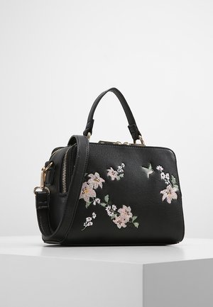 Czarna torebka z górnym uchwytem i odpinanym paskiem na ramię, ozdobiona różowo-białym kwiatowym haftem na gładkiej powierzchni.