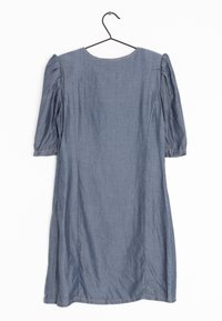 Denimmekko sinisestä kankaasta, lyhyet puff-hihat, pyöreä pääntie ja sivusaumat. Roikkuu mustalla koukulla valkoista taustaa vasten.